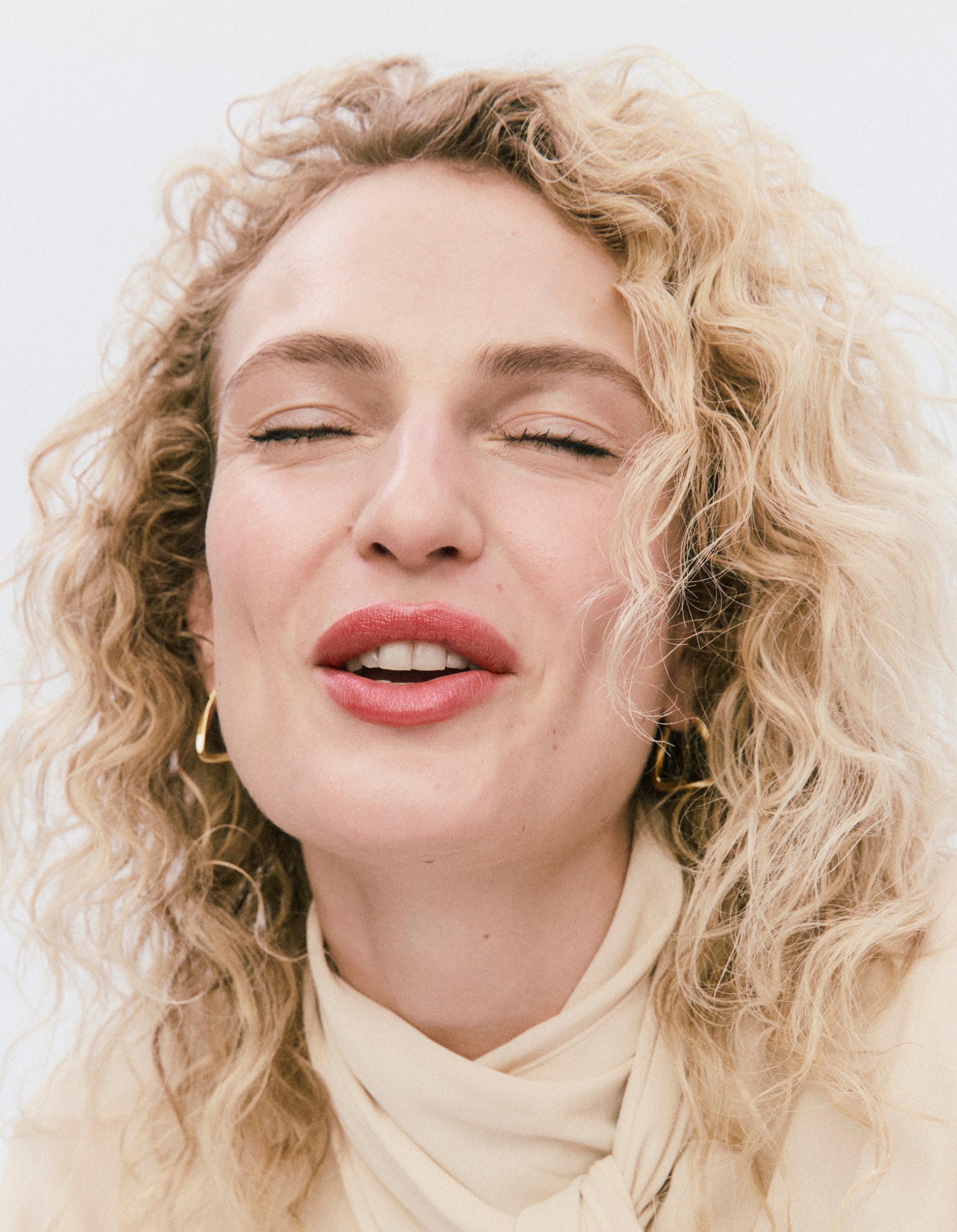 Displays a model with her eyes closed, smiling. 