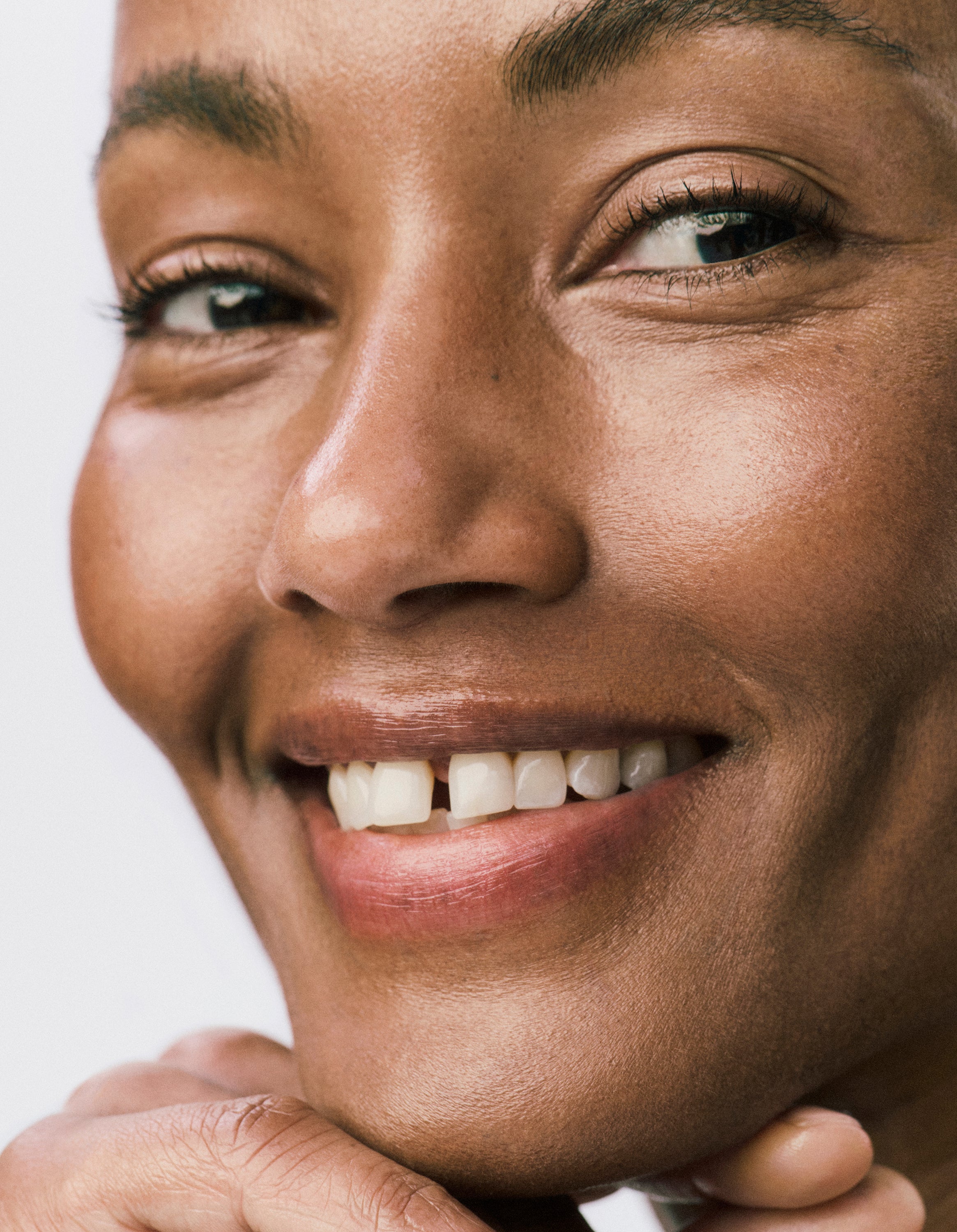 Displays a close up of a smiling model's face. 