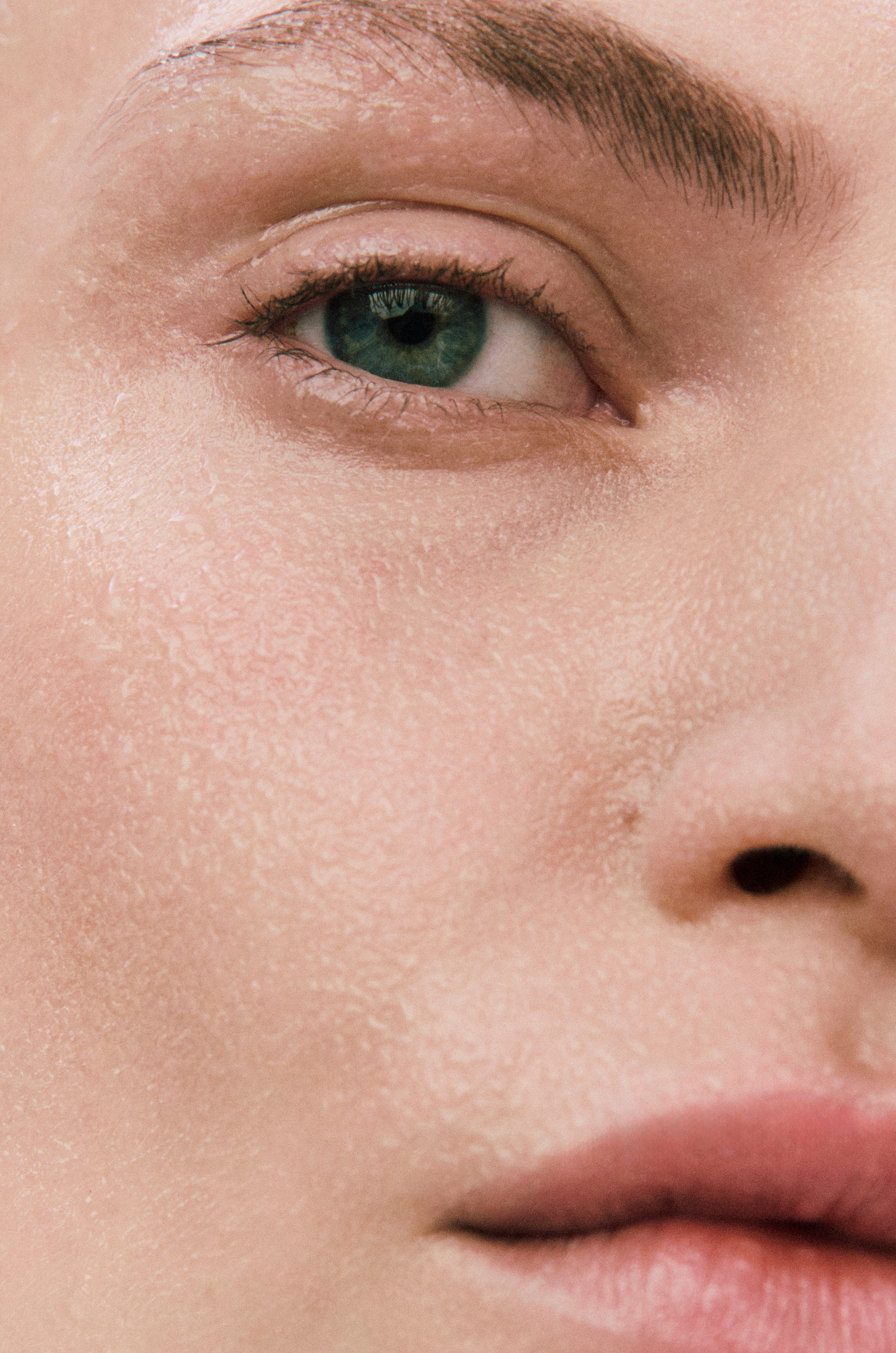 Displays half of a model's face with Counterglow Hyaluronic Moisture Mist applied.