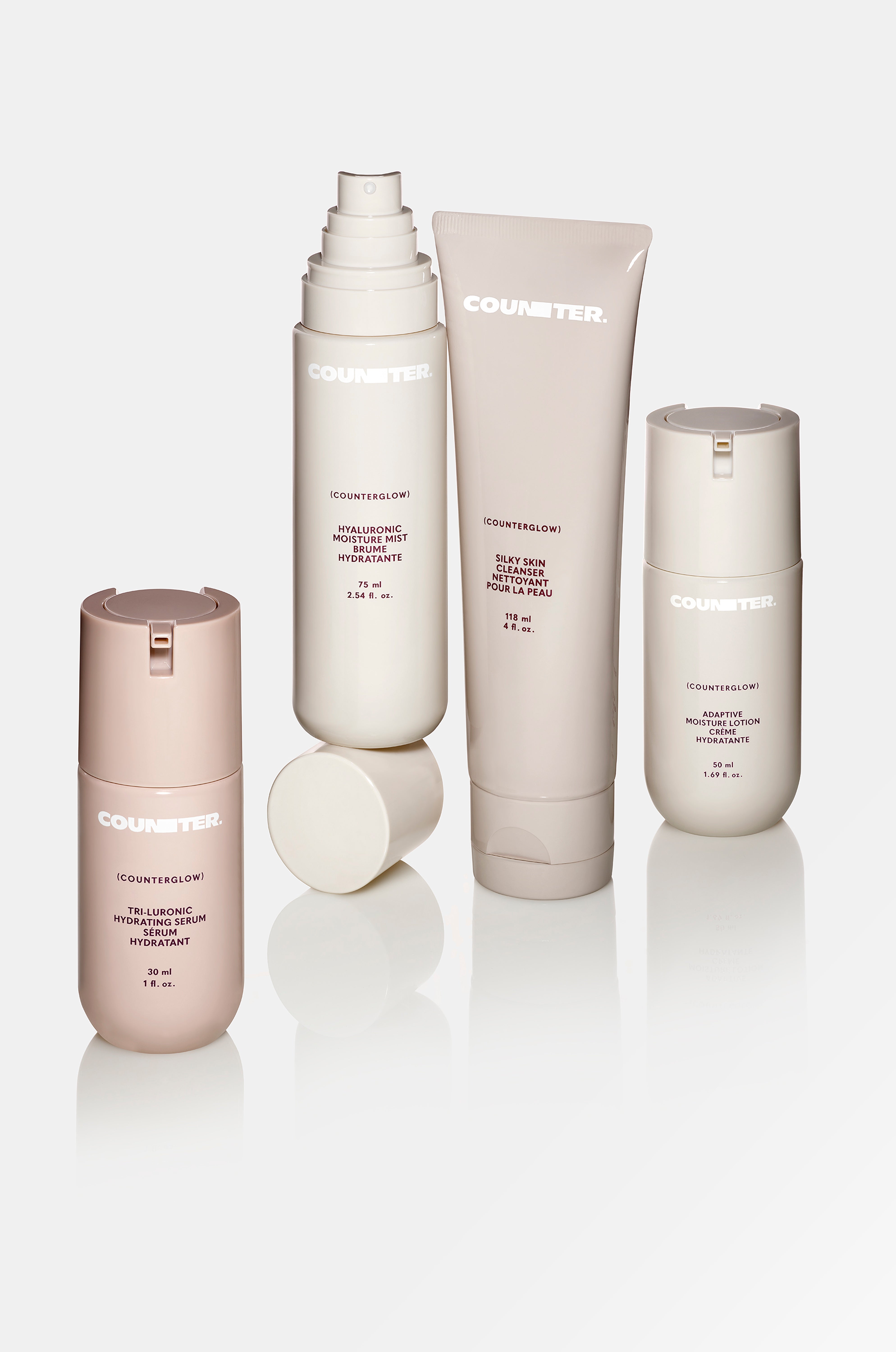 Displays the Counterglow products in a line on a mirrored surface. Each product is a different shade of neutral.