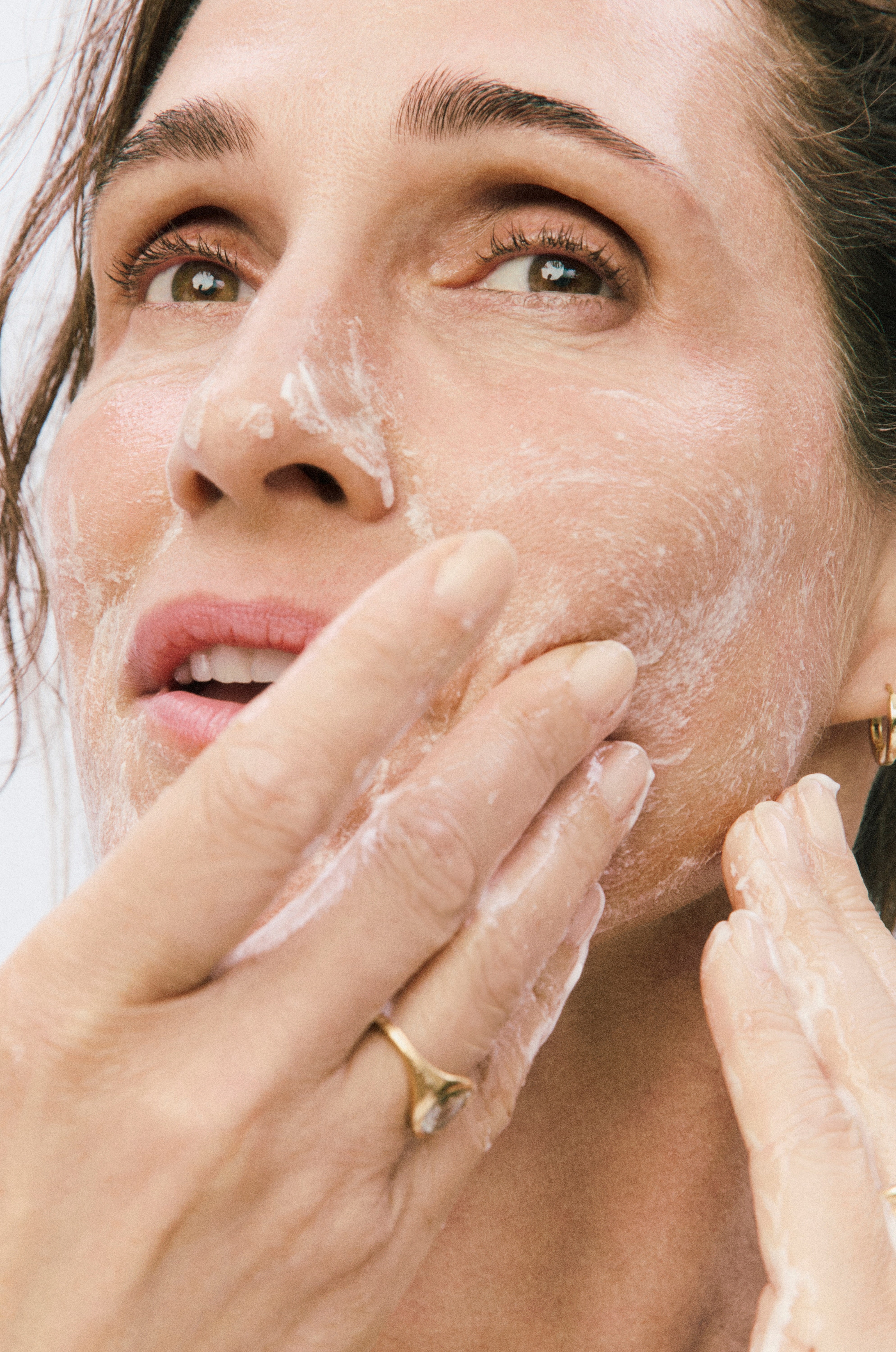 Displays model applying Silky Skin Cleanser to her face.