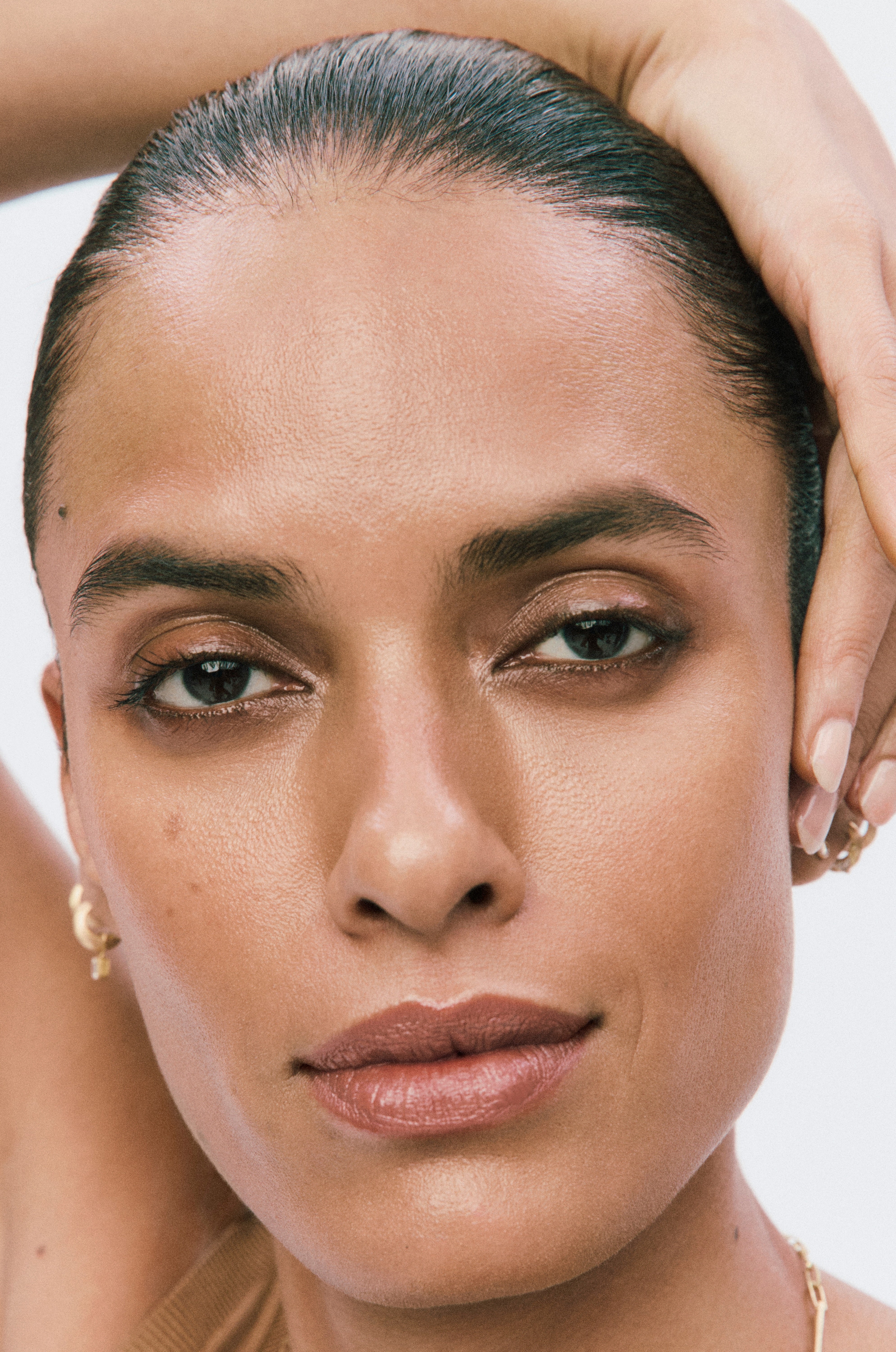 Displays woman's face with her hand overtop of her head wearing shade no4 of the Counter Dew Skin Product.
