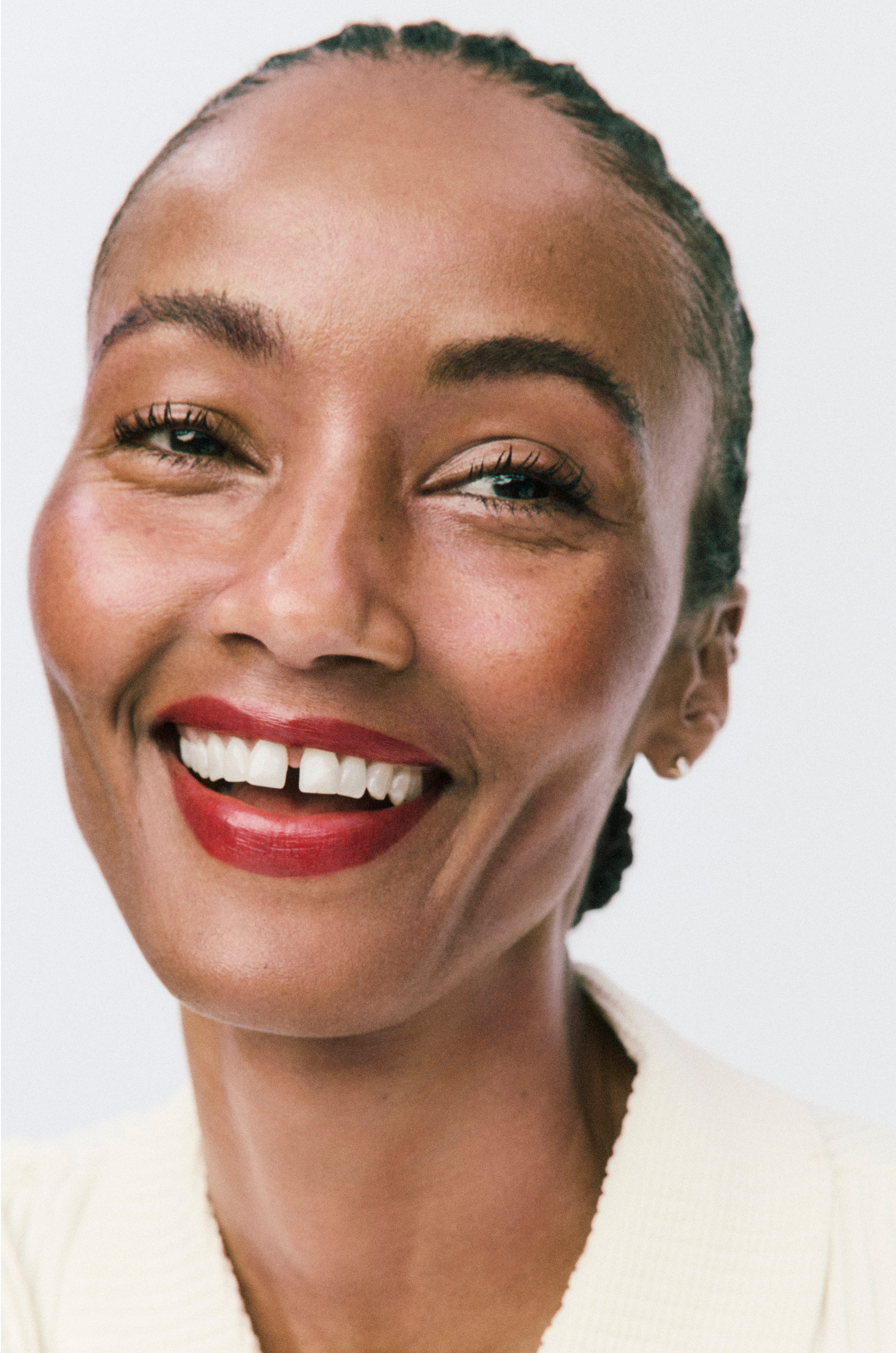 Woman with a bright smile wearing red lipstick against a white background