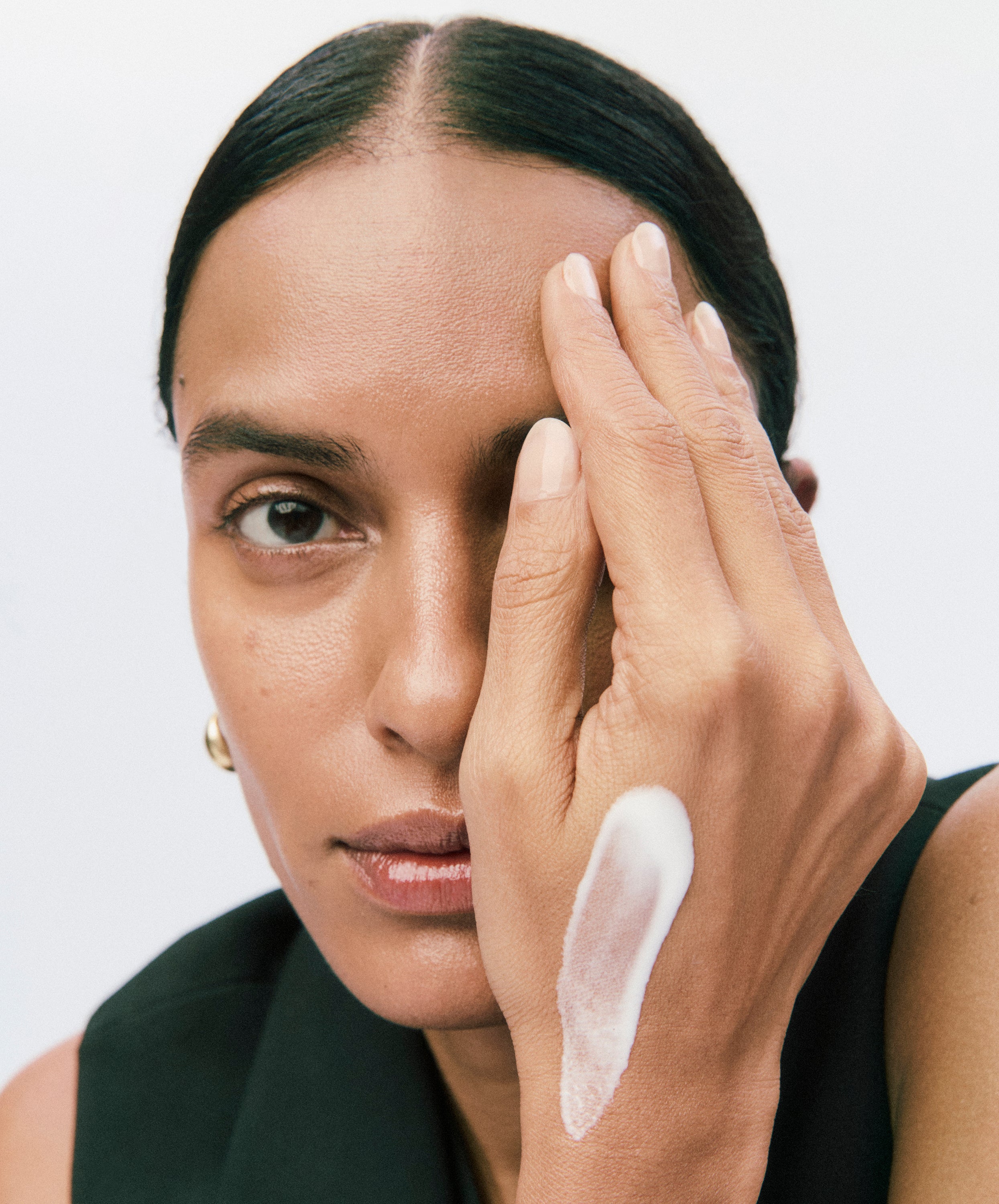 Displays a model covering half of her face with her hand. On her hand is the white smear of a Counter product.