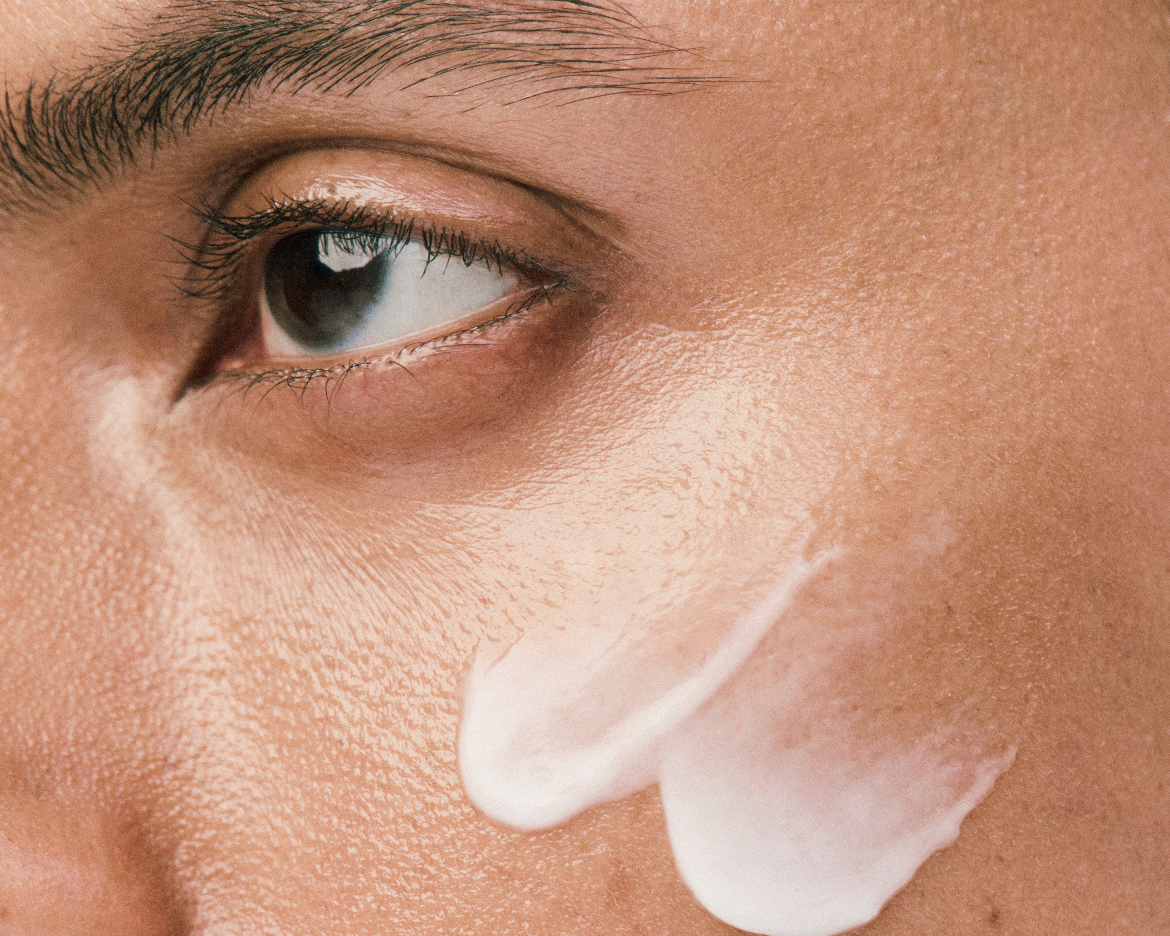 Displays a close up of a model's face with a sheer white Counter smear on her cheekbone.
