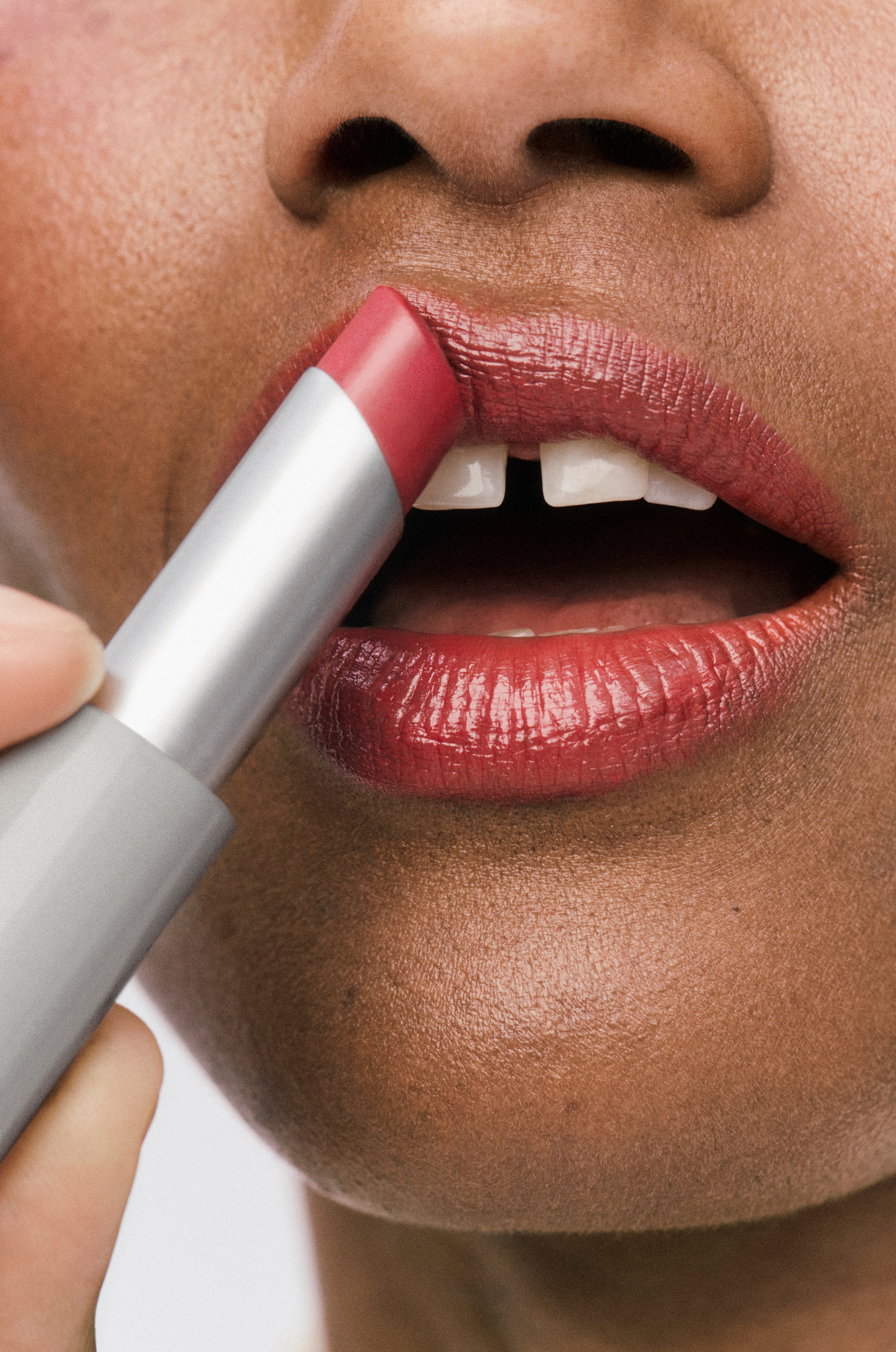 Displays a close up of a model's mouth where she is applying the Sheer Genius Conditioning Lipstick in Orchid.