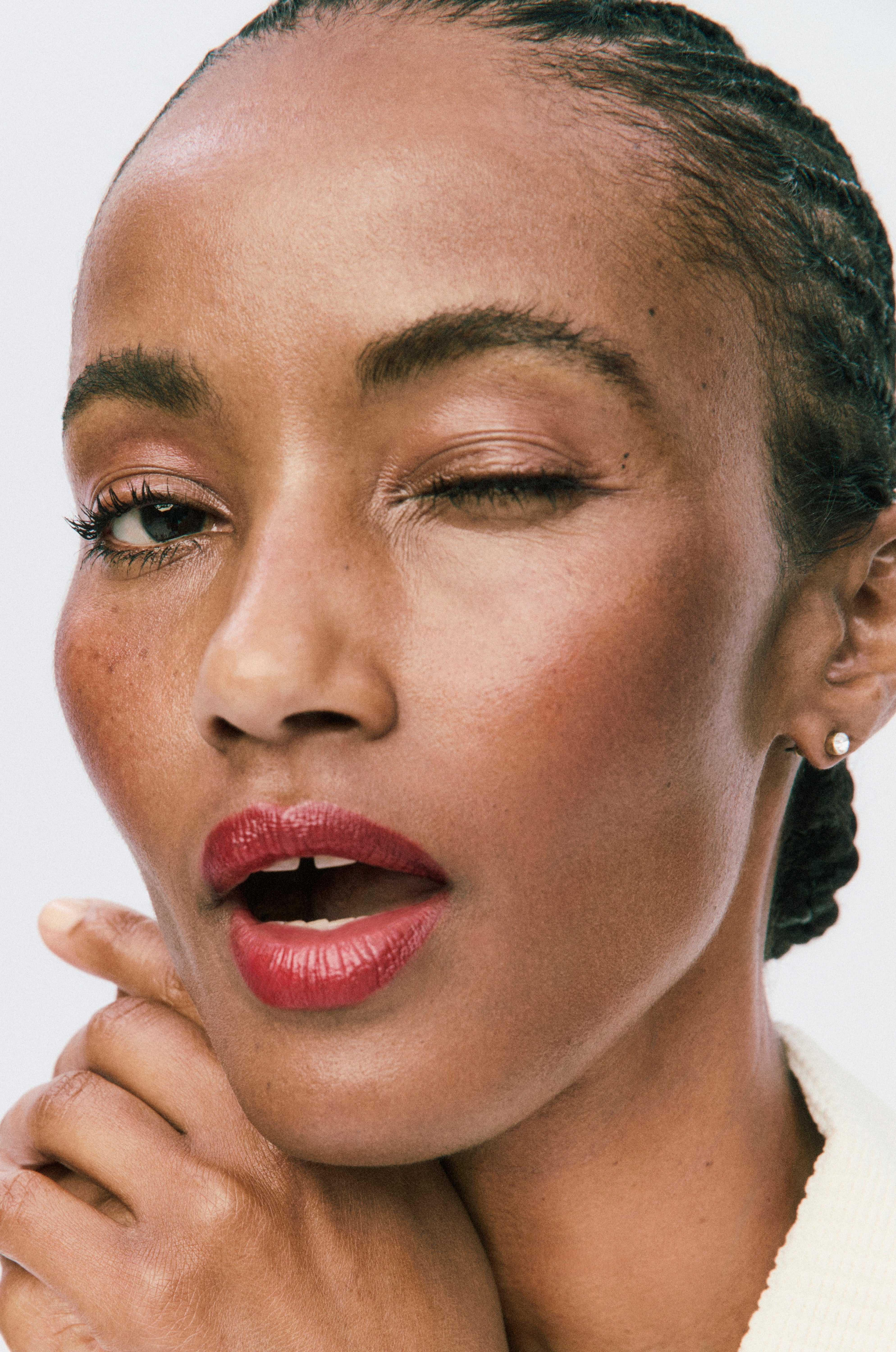Displays a photo of a winking model wearing the Sheer Genius Conditioning Lipstick.