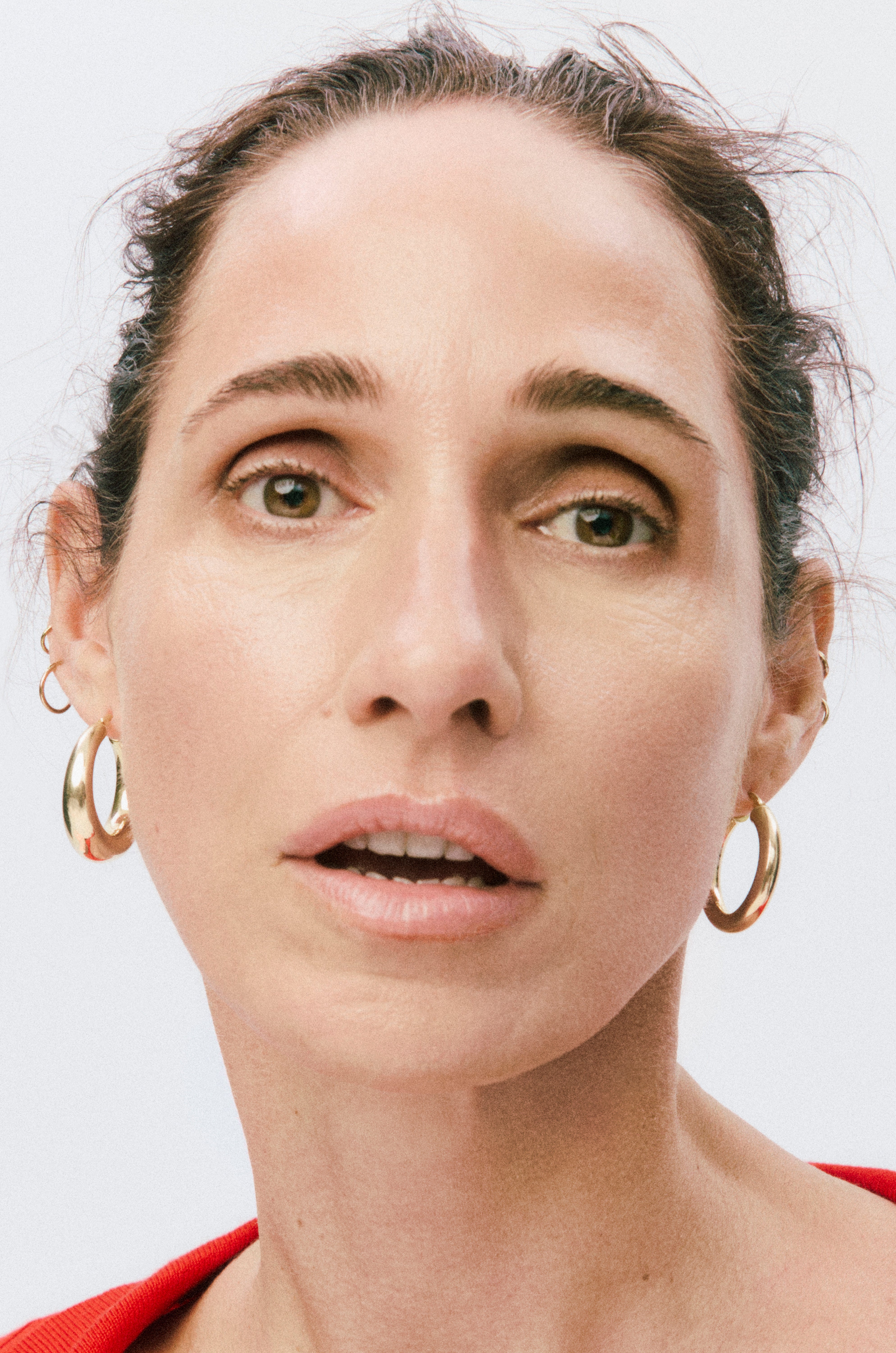 Close-up of a person with hoop earrings against a plain background