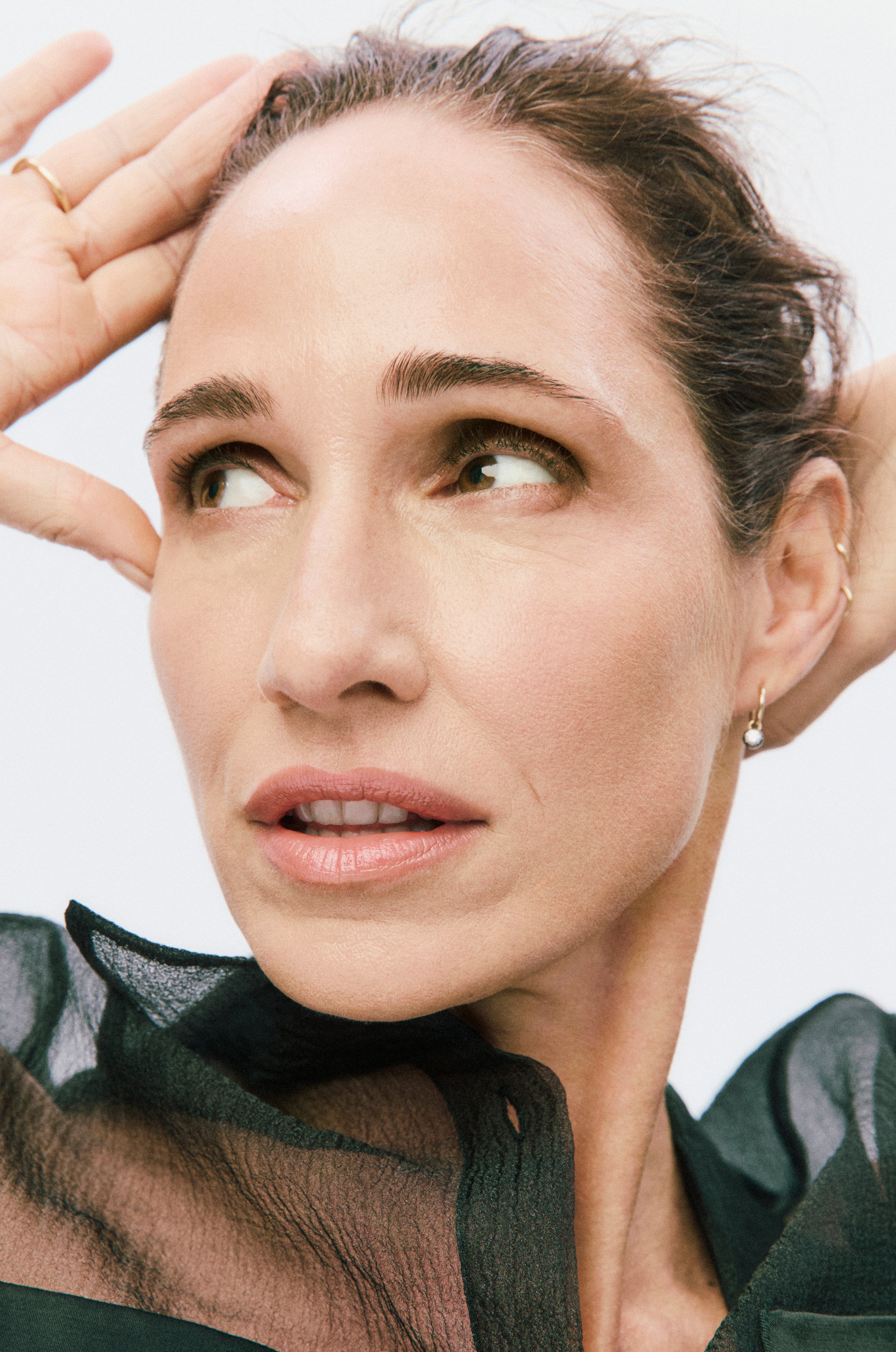 Close-up of a person with hands near their face against a light background