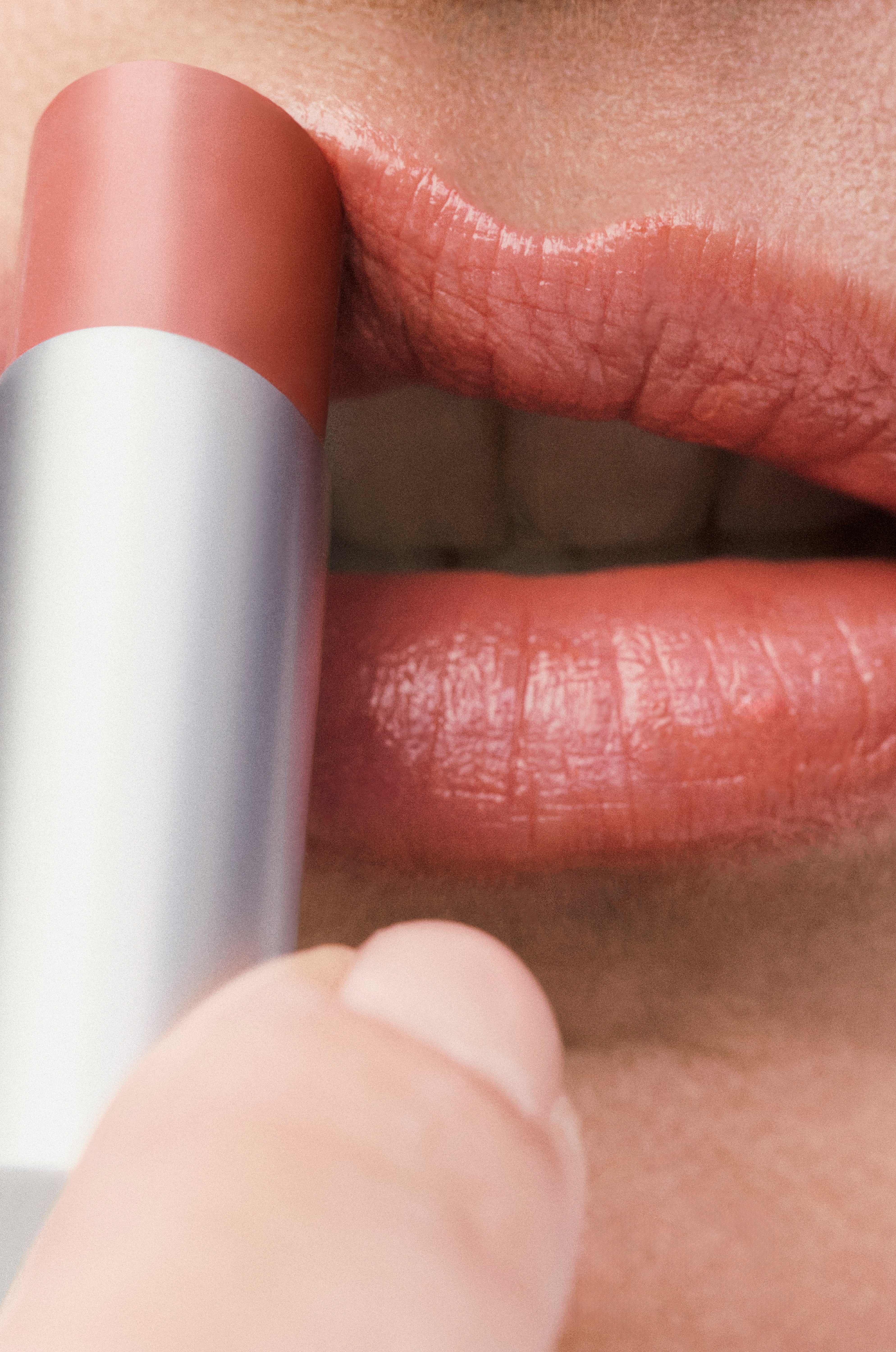 Displays a close up of a model's mouth where she is applying the Sheer Genius Conditioning Lipstick in Twig.