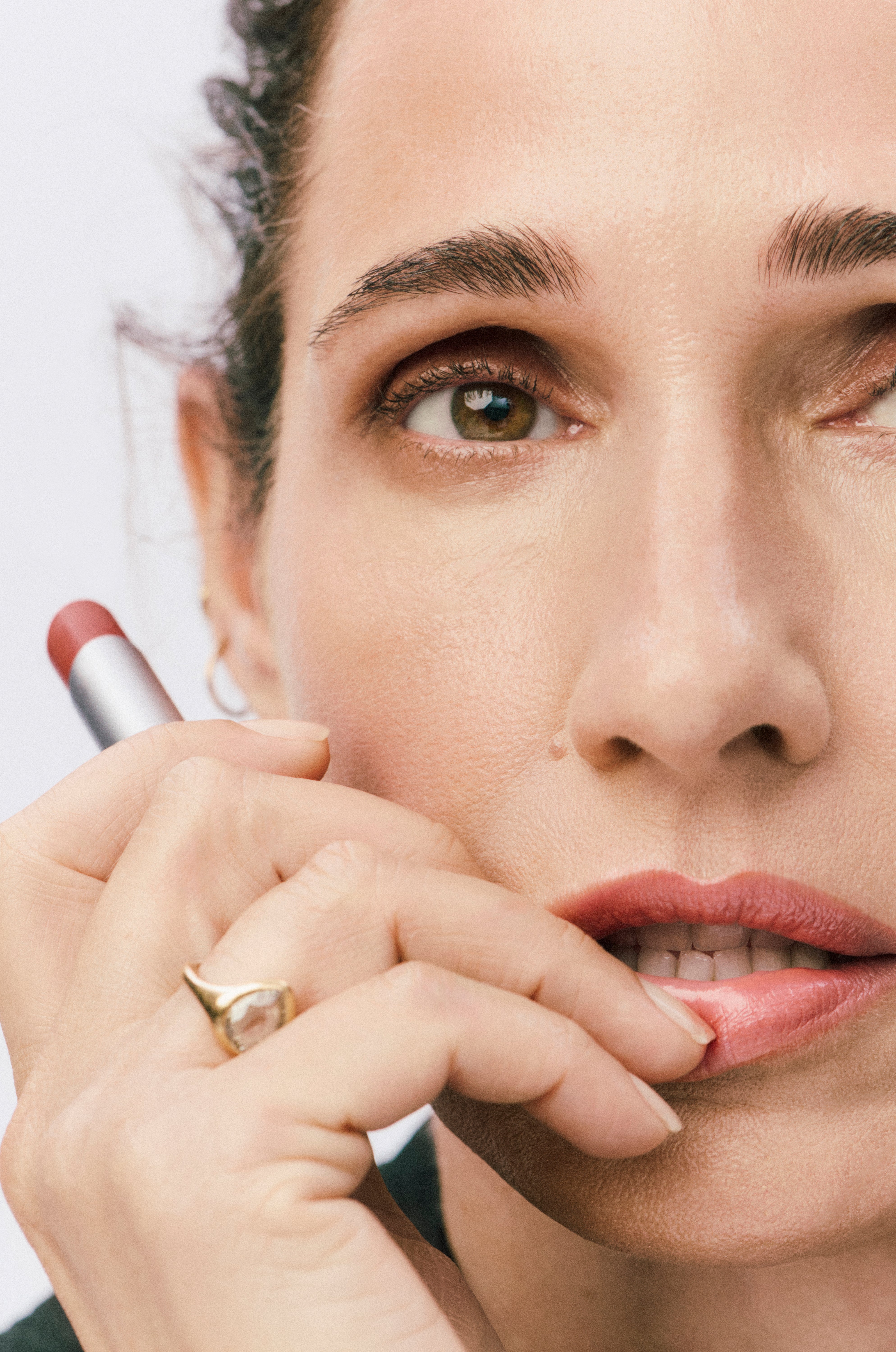 Close-up of a woman applying lipstick with a blurred background