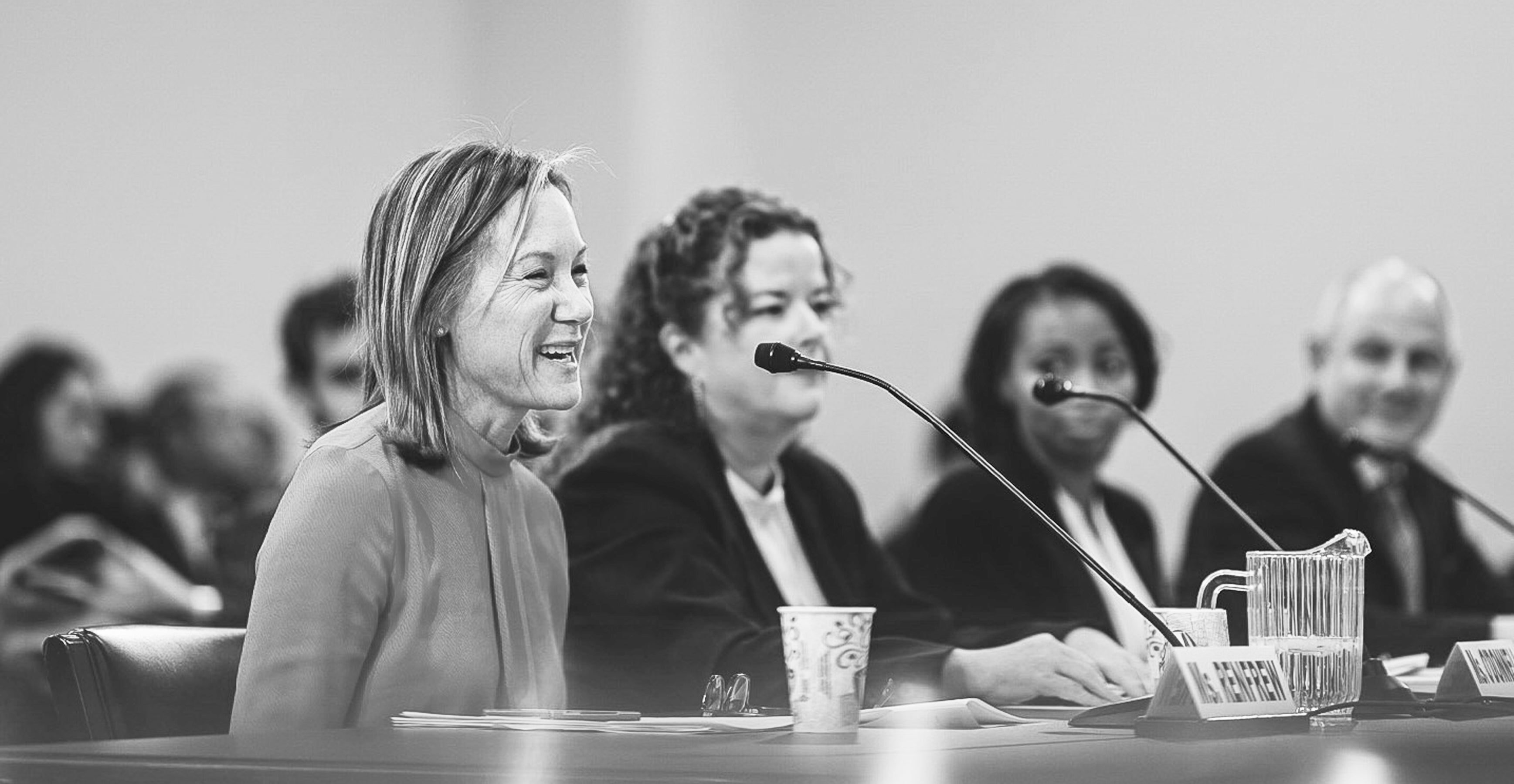 Displays Gregg Renfrew in Washington DC speaking into a microphone in front of a crowd of women.