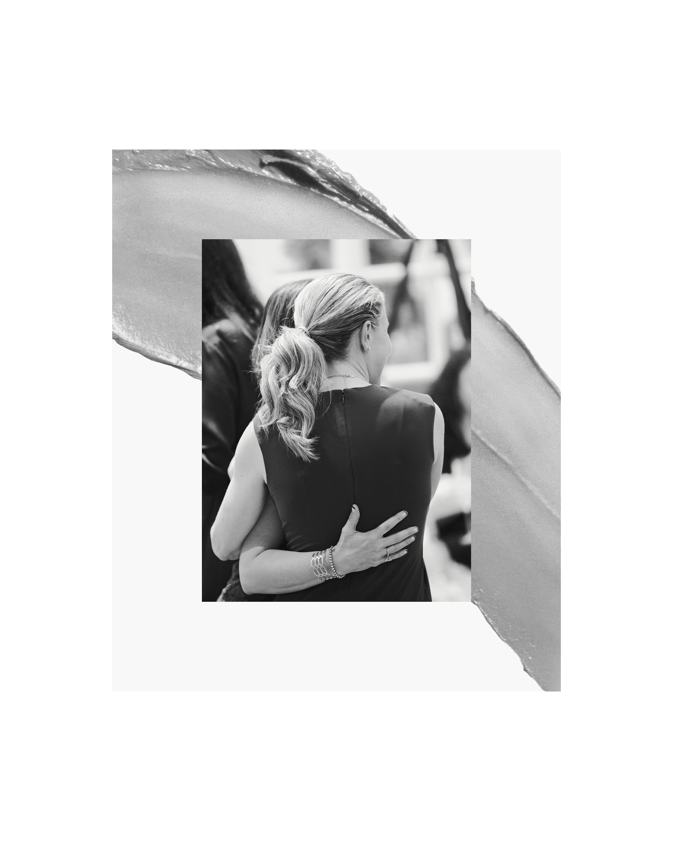 Displays two women embracing which is overlayed on a black and white smear of product.