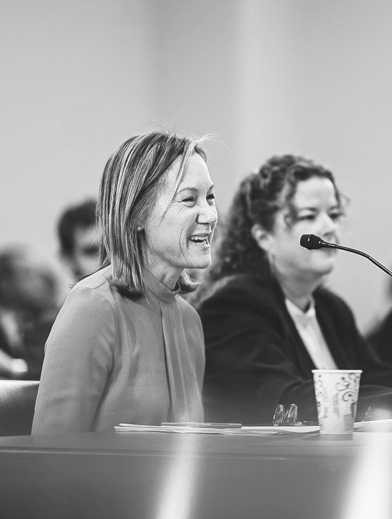 Displays Gregg Renfrew in Washington DC speaking into a microphone in front of a crowd of women.