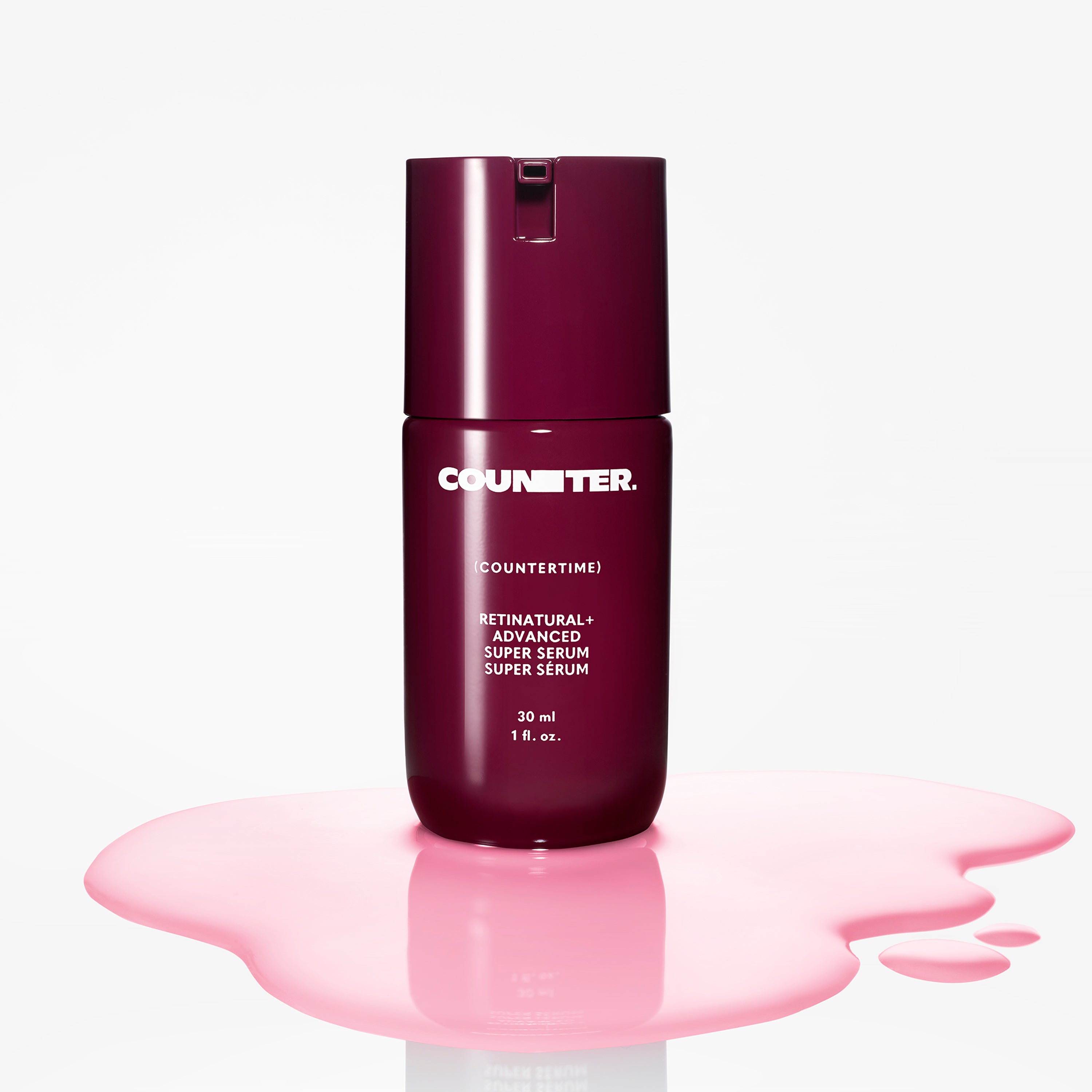 Displays a burgundy bottle of the Countertime Retinatural plus Advance super serum in a pool of pink product. 